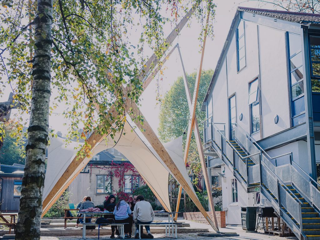 Students studying under Squirrel Hall, a wooden structure in the grounds of The King Alfred School
