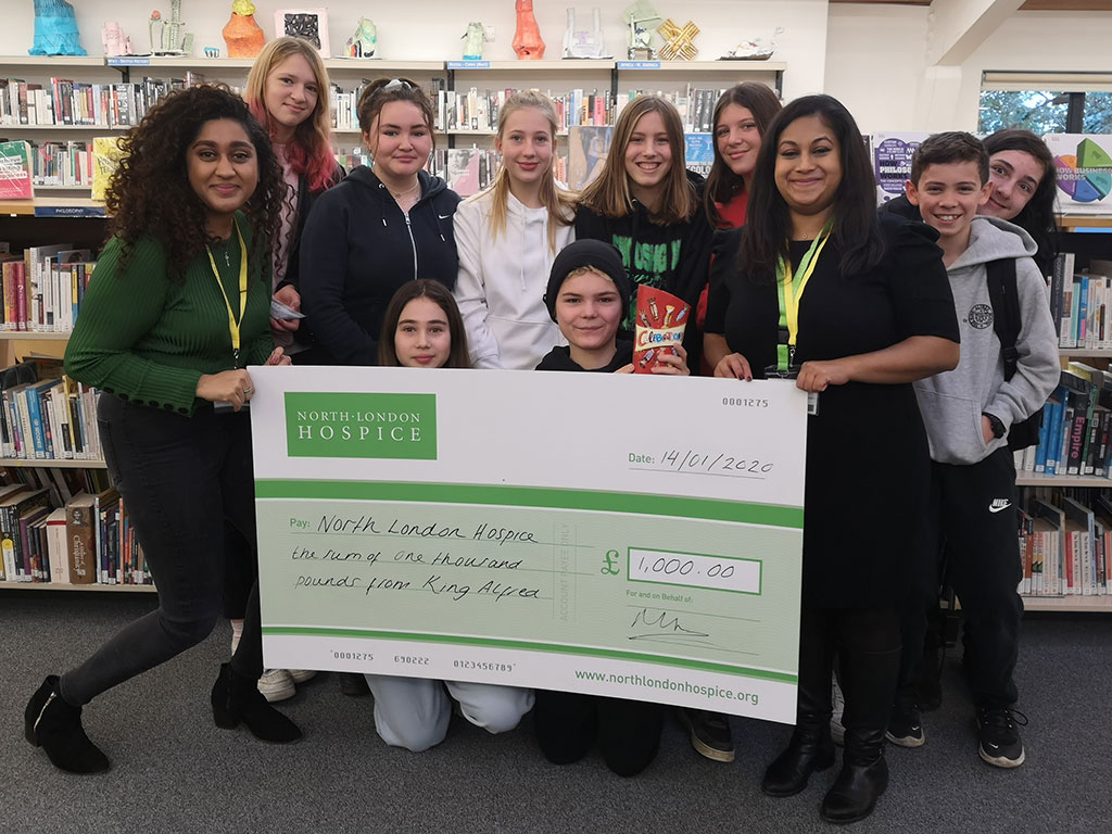 Children and staff holding a large £1000 check to the North London Hospice from King Alfred School
