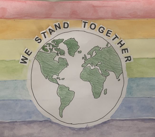 drawing of the earth and the words 'we stand together' with the colours of the rainbow in the background