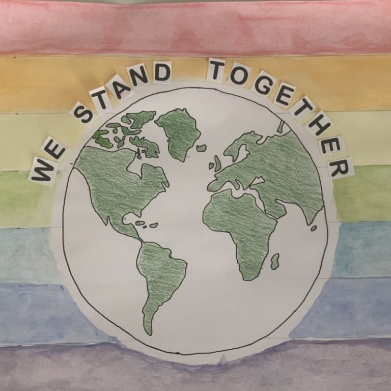 drawing of the earth and the words 'we stand together' with the colours of the rainbow in the background