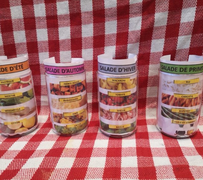 Four jars holding paper with pictures of the food included in different types of salads