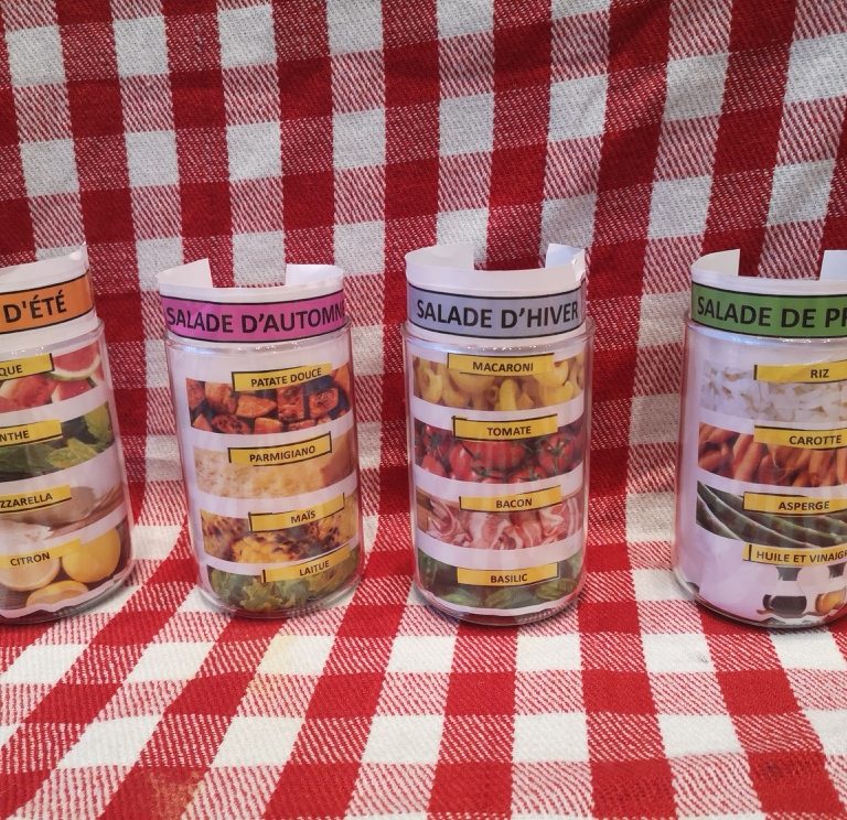 Four jars holding paper with pictures of the food included in different types of salads