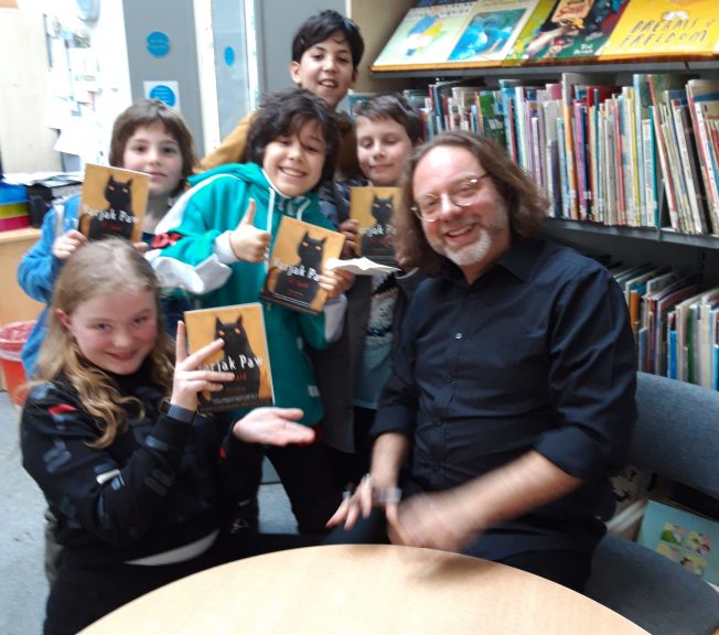 Children holding books with an adult in the library
