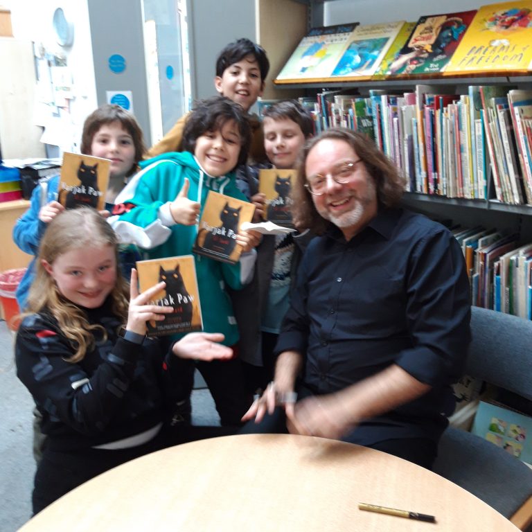 Children holding books with an adult in the library