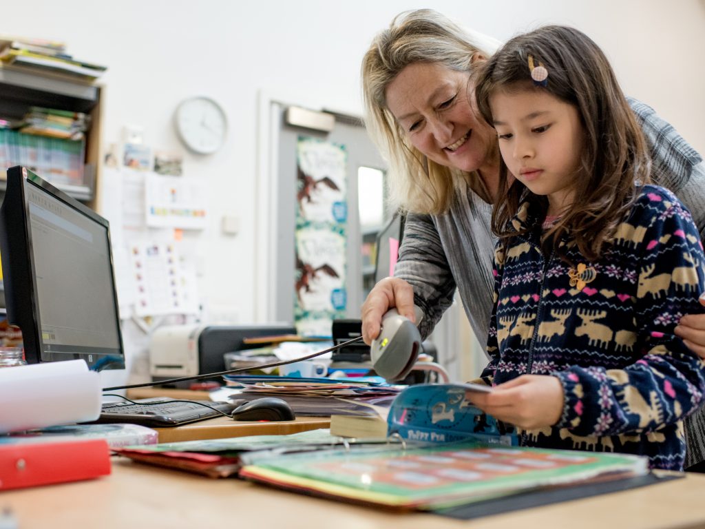 Librarian checking out a library book with a child