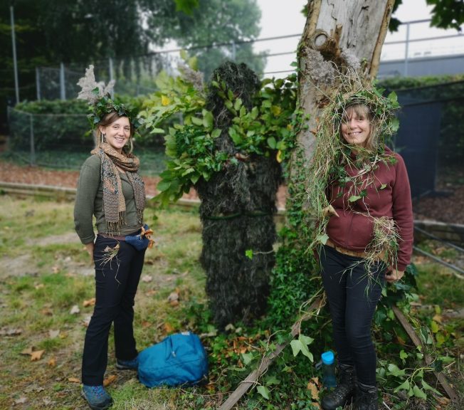 Two women wearing leaves on their heads