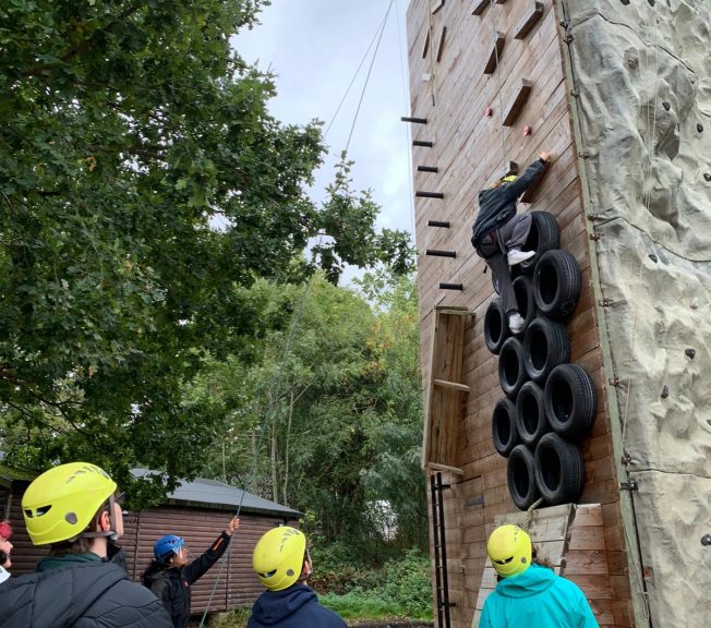 Student climbing on a wooden structure