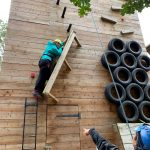 Student climbing on a wooden structure