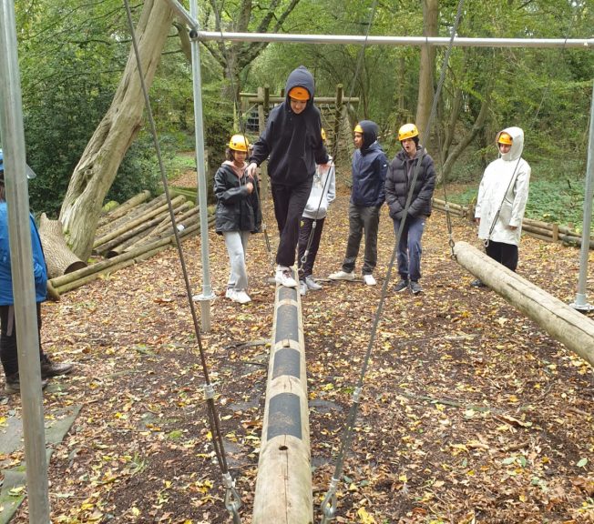 Student walking across a wooden pole