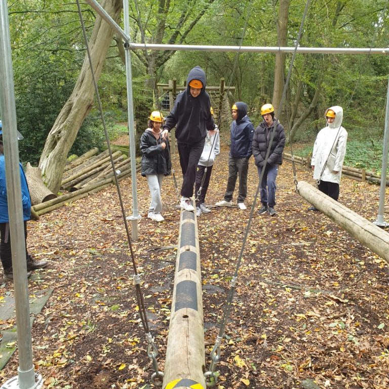 Student walking across a wooden pole