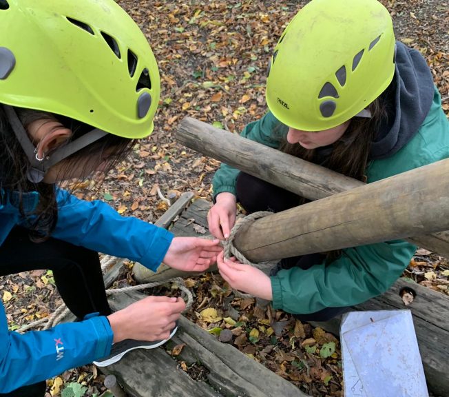 Students tying rope to a wooden structure