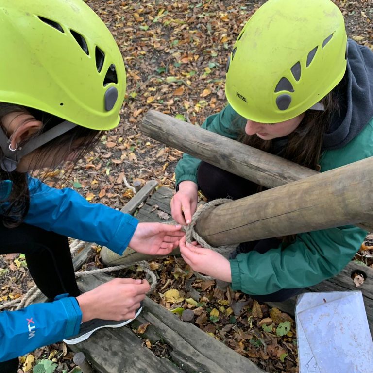 Students tying rope to a wooden structure