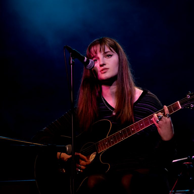 Student singing and playing guitar for school concert