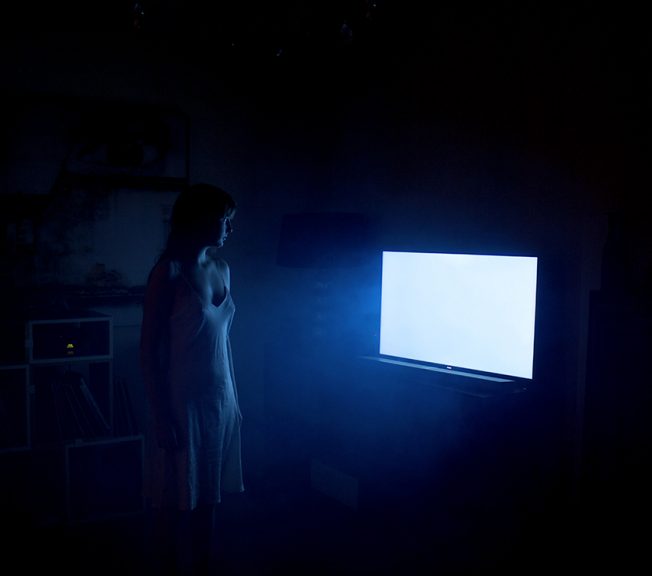 Photograph of a woman and a light emitting from a blank screen