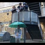 Sixth form students shooting a film, pouring water on an umbrella