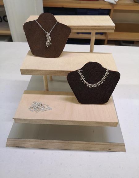 three silver necklaces on a wooden structure