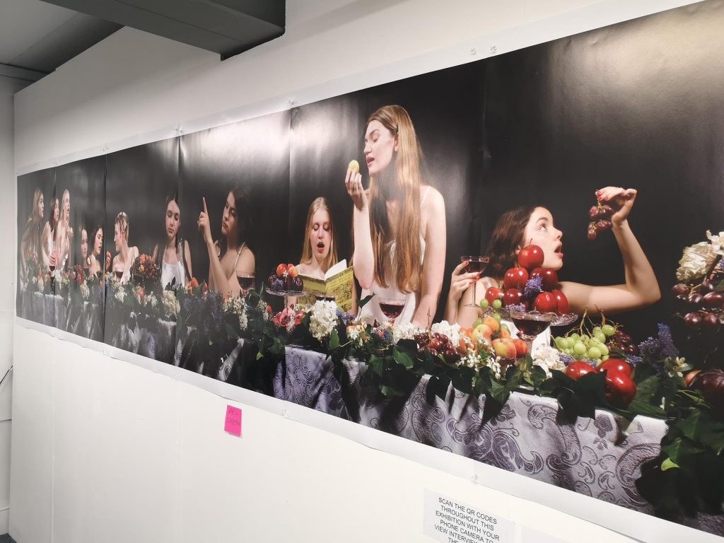 Students sitting at a long table with fruit and flowers