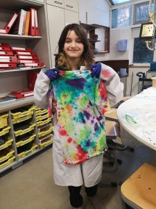 student holding up tie dyed shirt