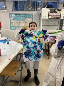 student holding up tie dyed shirt