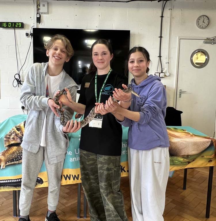 students and visitor holding a snake