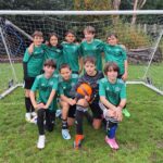 Boys from The King Alfred School dressed in green football kit, standing in front of a goal.