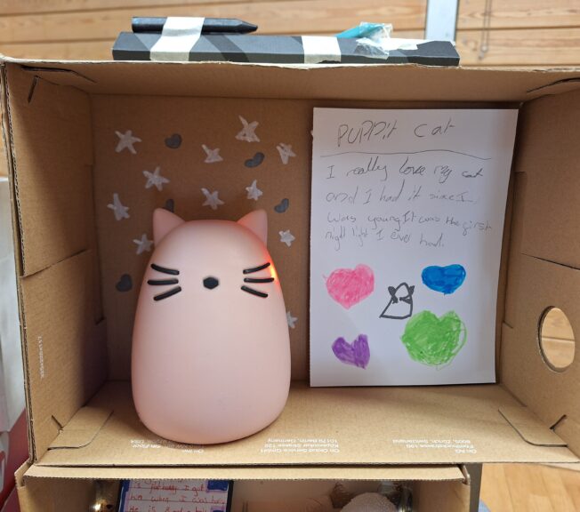 A shoebox with a cute cat-like nightlight inside. A note reads: 'Puppit Cat. I really love my cat and I had it since I was young. It was the first night light I ever had.'