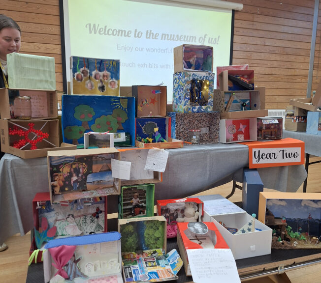 Decorated shoeboxes displayed on a table with a sign that reads 'Year Two'