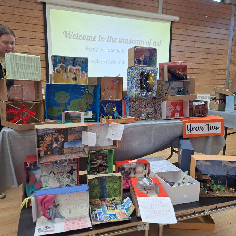 Decorated shoeboxes displayed on a table with a sign that reads 'Year Two'