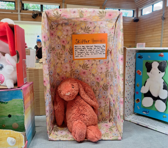A shoebox on its side decorated with floral paper and a pink toy bunny inside. A note reads: 'This is my special bunny. My mummy and daddy got her for me when I was a small baby. I snuggled her every day when I was a baby. I still love how soft she is.'