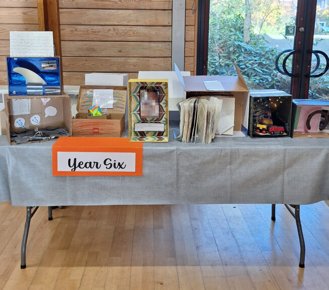 Decorated shoeboxes displayed on a table with a sign that reads 'Year Six;