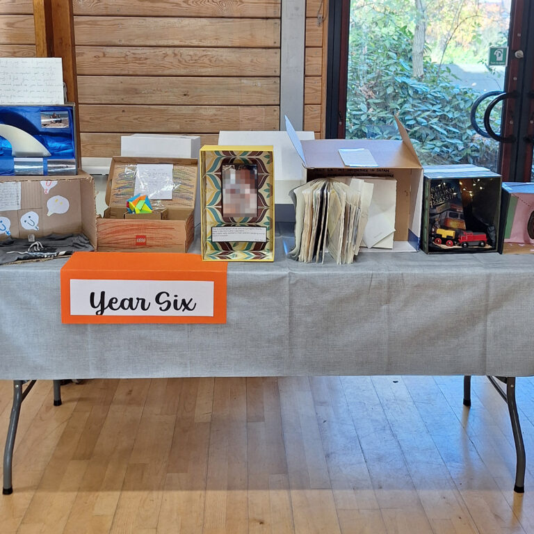Decorated shoeboxes displayed on a table with a sign that reads 'Year Six;