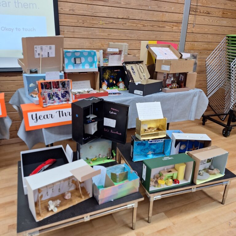 A selection of decorated shoeboxes on a table, with a sign that reads 'Year Three'