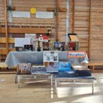 A table of decorated shoeboxes on a table in a wooden school gym. A sign reads 'reception'.