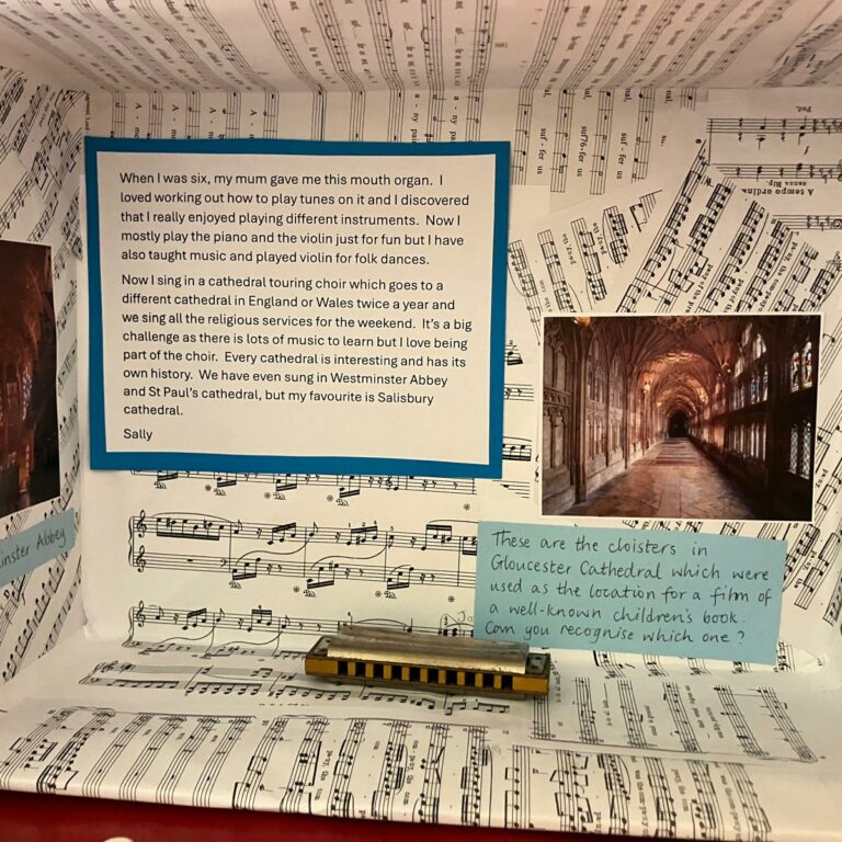 A shoebox on its side decorated with sheets of music, a mouth organ and pictures of cathedrals. A note reads: 'When I was six my mum gave me this mouth organ. I loved working out how to play tunes on it and I discovered that I really enjoyed playing different instruments. Now I mostly play the piano and violin just for fun, but I have also taught music and played violin for folk dances. Now I sing in a cathedral touring choir, which goes to a different cathedral in England of Wales twice a year and we sing all the religious services for the weekend. It's a big challenge as there is lots of music to learn but I love being part of the choir. Every cathedral is interesting and has its own history. We have even sung in Westminster Abbey and St Paul's cathedral, but my favourite is Salisbury Cathedral.'