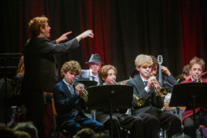 A teacher conducts the student jazz band on stage