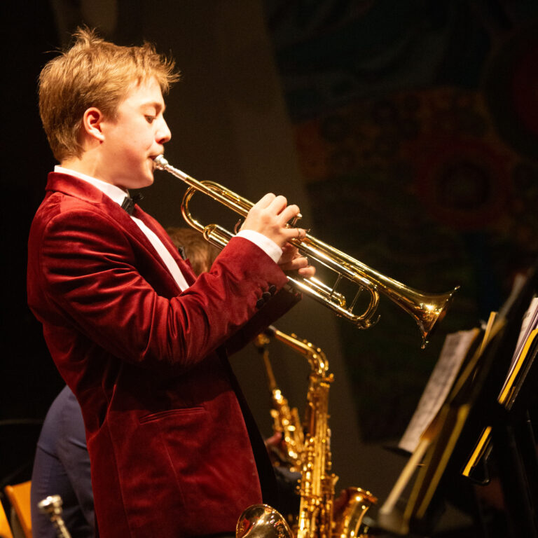 A student on stage at the KAS Jazz evening playing the trumpet