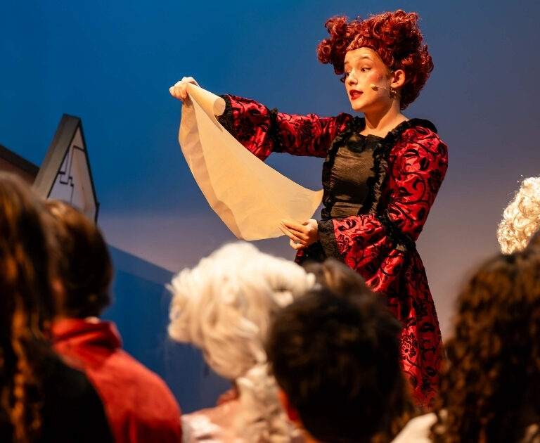 Female actor reads from a script on stage