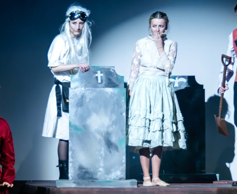 Actors around a gravestone on stage