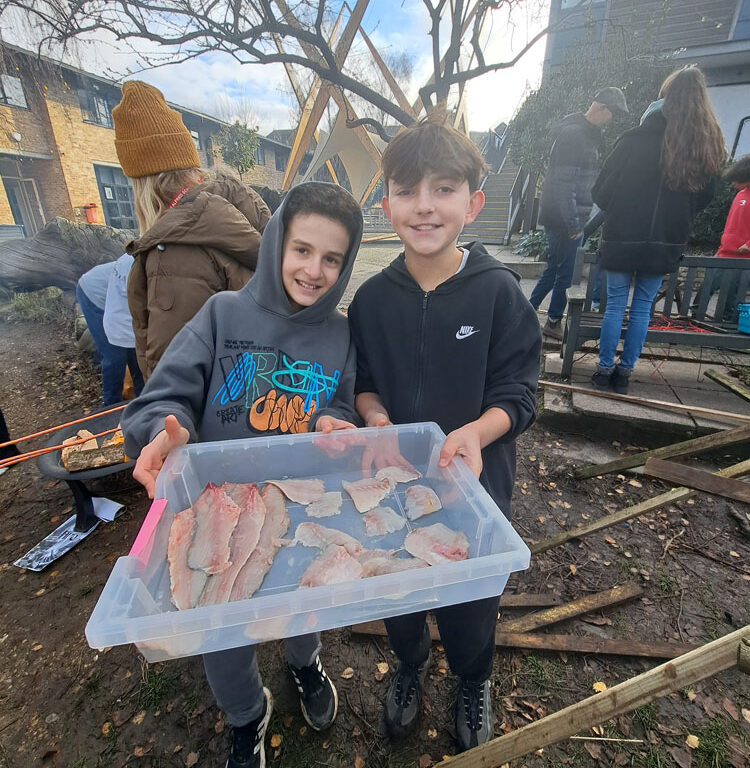 students at The King Alfred School holding freshly filleted fish as part of a project on survival