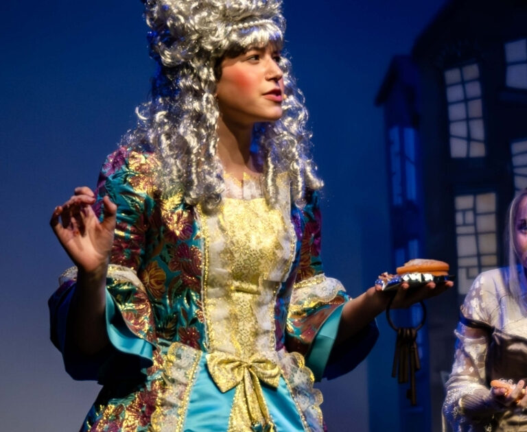 Actor wearing an elaborate Regency wig on stage