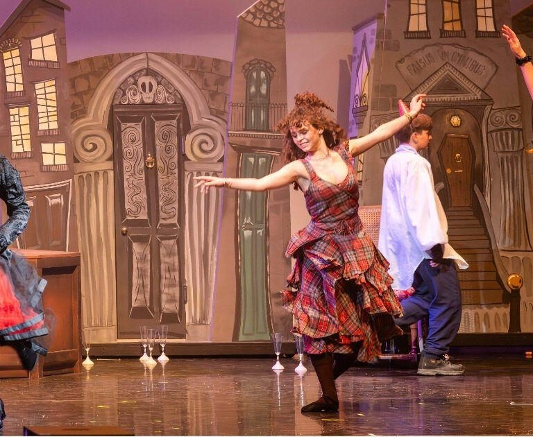 Three female performers dance on stage