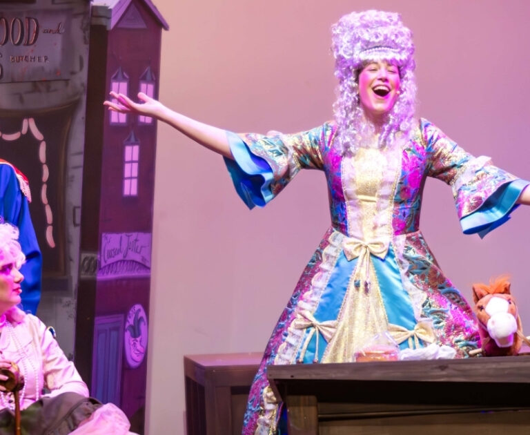 An actor sings with her arms out