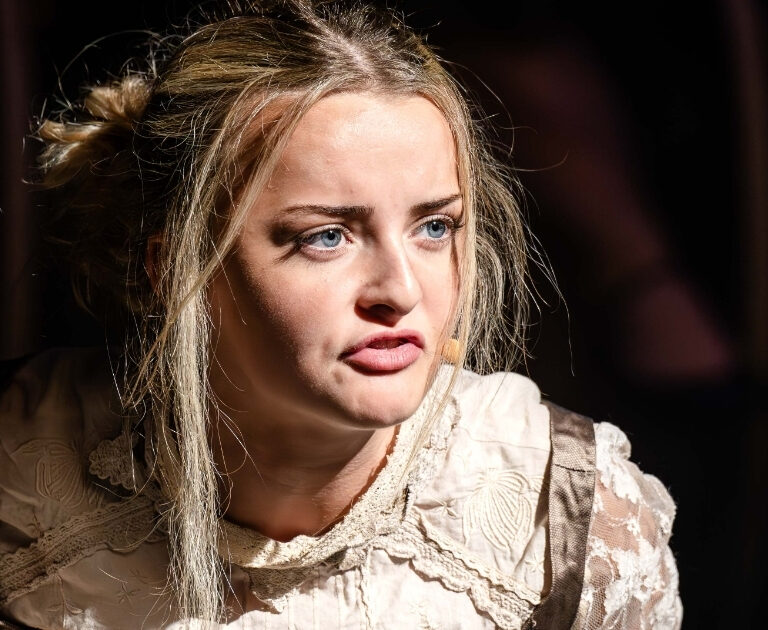 Close-up of a blonde girl singing, her face full of emotion