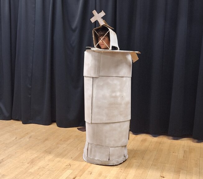 A student wearing a King chess piece sculpture