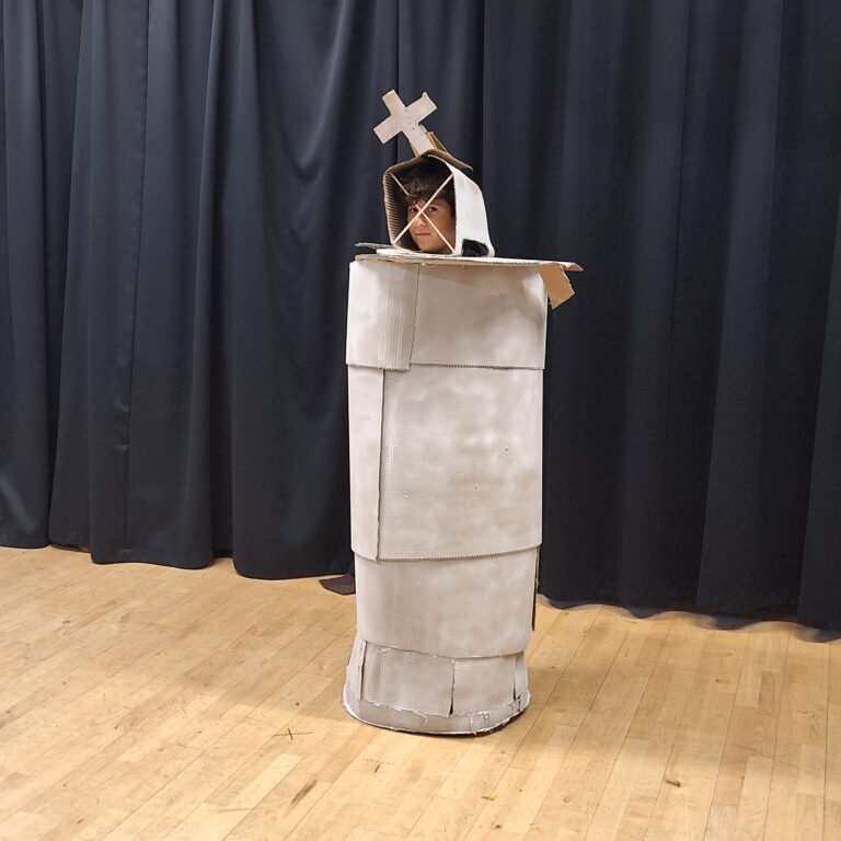 A student wearing a King chess piece sculpture