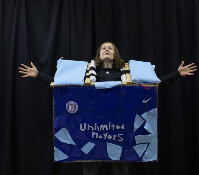 A student wears an abstract fashion design, featuring a blue box with the words 'Unlimited Players' on the front