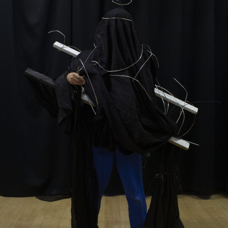 A student wears an abstract fashion design featuring a black cloak and silver wire