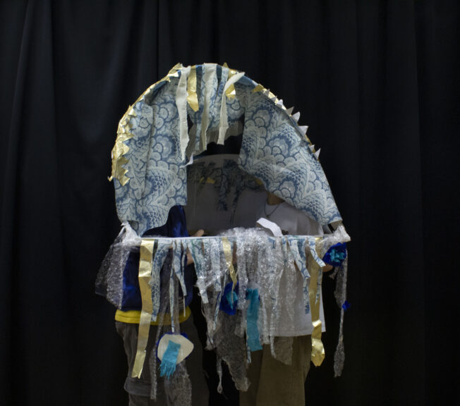 Two students wear an abstract structure designed to look like a jellyfish
