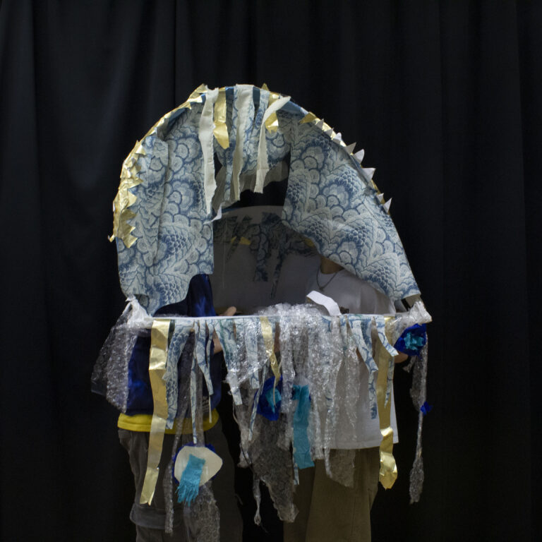 Two students wear an abstract structure designed to look like a jellyfish