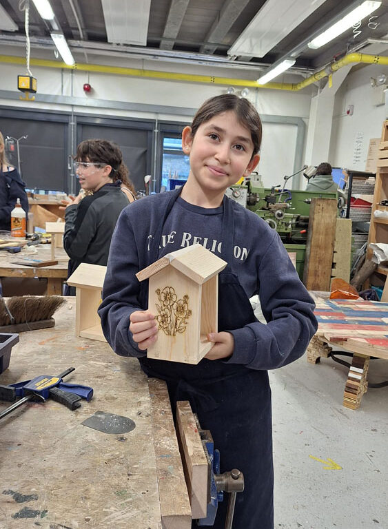 A student holds up a finished bird feeder